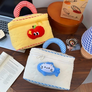 Detail of heart-quilted travel makeup bags with plush apple and fish zipper charms