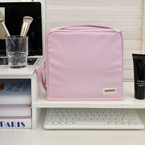 Pink waterproof nylon cosmetic bag with top handle organized on a desk storage shelf