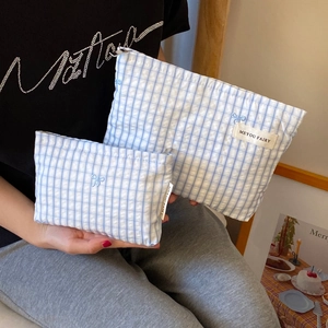 Close-up of blue gingham pouches set with bow embroidery and textured fabric detail