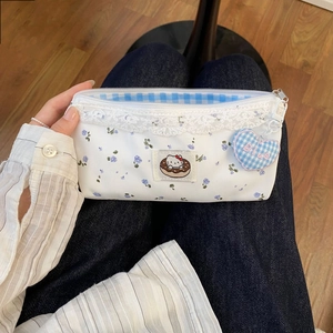 Close-up of floral cat pencil case with lace trim and blue heart charm detail
