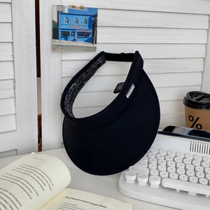 Detail of black open top sun hat with wide brim on a table with aesthetic lifestyle decor