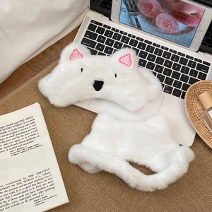 Detail of white plush Westie dog sleep mask with pink plaid ears on laptop keyboard