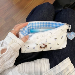 Close-up of floral pencil case with lace trim, Hello Kitty patch and heart charm