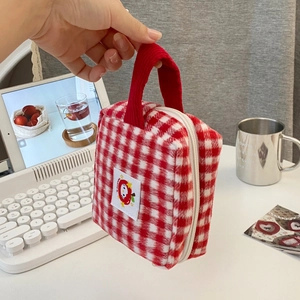 Detail of red checkered vanity bag featuring Hello Kitty logo with a corduroy handle