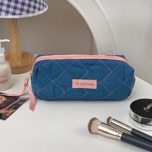 Detail of denim blue cosmetic bag with pink quilted stitching and the jolly house label