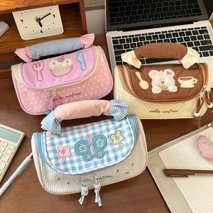 Detail of macaron-colored fabric pencil cases with patchwork design and ruffled handles