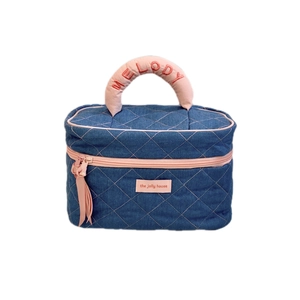 Quilted denim makeup bag with pink piping and Melody embroidery for travel storage