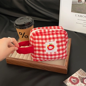 Detail of red checkered plush makeup bag with Hello Kitty embroidery and sturdy handle