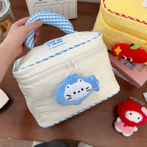 Detail of cream quilted makeup bag with heart patterns and blue cat plush zipper charm
