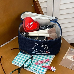 Detail view of denim cosmetic bag with cat embroidery and makeup items inside