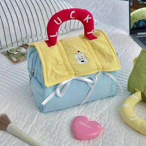 Detail of blue quilted makeup bag with red Lucky handle and cute bear embroidery