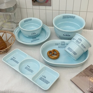 Détail de la vaisselle en céramique bleu clair avec inscription noire sur une nappe