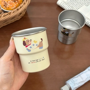 Close-up of stainless steel dachshund dog mug being held in a cozy home setting