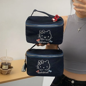 Mirror selfie showing two sizes of denim Hello Kitty makeup bags with red bow zippers