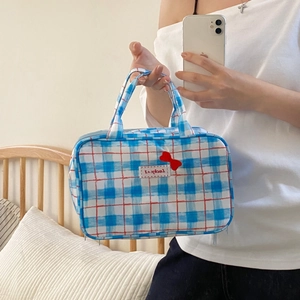 Detail of blue plaid makeup bag with red bow decoration and soft fabric texture