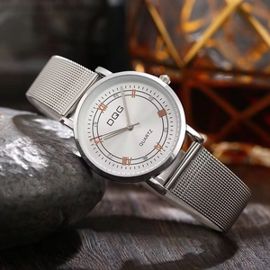 Detailed close-up of a silver mesh strap watch with rose gold Roman numerals on dark stone