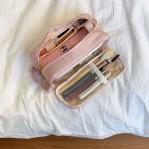 Pink multi-compartment travel toiletry bag showing internal mesh pockets for brushes
