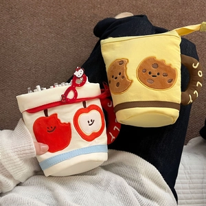 Close-up of plush cartoon pouches with apple embroidery and Hello Kitty charm