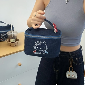 Detail of blue denim cosmetic bag with large white cat embroidery and top handle