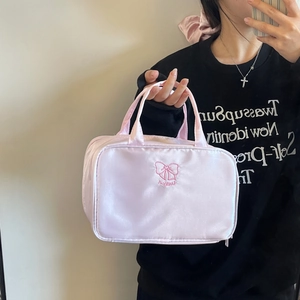 Detailed close-up of pink satin makeup bag featuring a bow and LUCKY embroidery