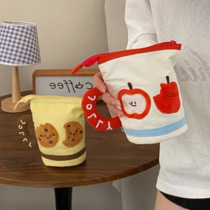Detail of canvas cup-shaped pencil cases with cute apple and cookie embroidery patterns