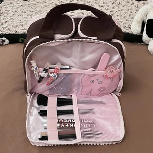 Macro view of partitioned makeup bag showing brown canvas exterior and pink nylon lining