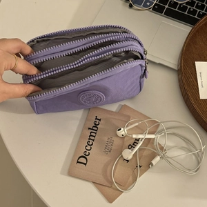 Gros plan d'un portefeuille violet en tissu à trois fermetures éclair sur un bureau