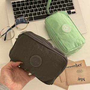 Détails du tissu en nylon léger et du logo sur les pochettes à monnaie zippées
