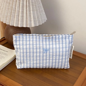 Detail of blue and white checkered bag with delicate bow embroidery and woven brand label