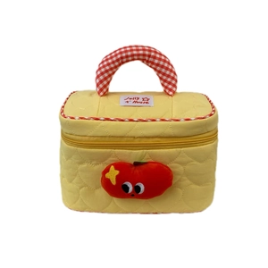 Quilted yellow makeup bag with apple patch and red checkered handles on white backdrop