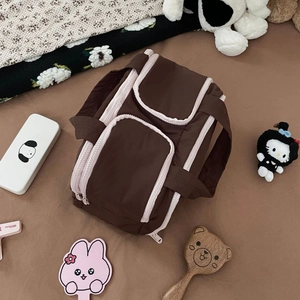 Macro detail of brown quilted makeup bag with pink zippers and multiple compartments