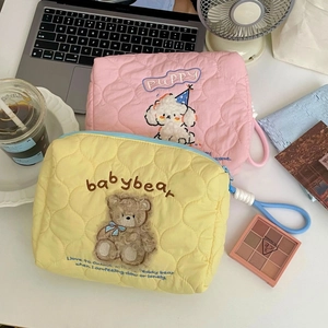 Close-up of quilted makeup bags with cute bear and puppy embroidery on white desk