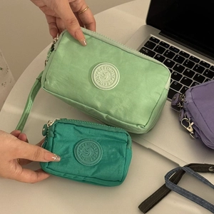 Pochettes en nylon vert avec dragonne, fermeture zippée et détail du logo rond