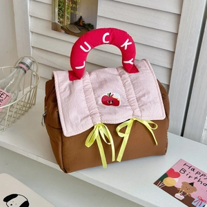 Detail of quilted makeup bag with red Lucky handle and cute apple embroidery patch