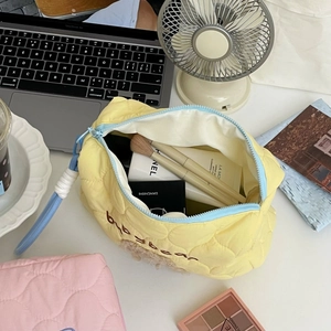 Macro view of yellow quilted cosmetic bag with blue zipper and plush bottom detail