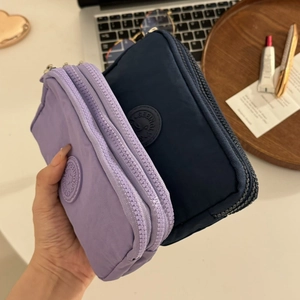 Détail de deux porte-monnaie en nylon violet et bleu marine à triple fermeture éclair