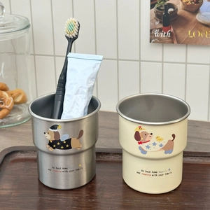 Detail of stainless steel cups with cute cartoon dog illustrations on wooden tray