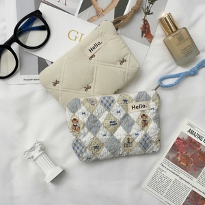 Detailed view of quilted cotton mini pouches with bow embroidery and bear patterns