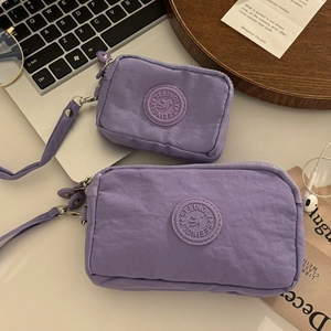 Détail de pochettes en nylon violet à triple fermeture éclair avec dragonne sur un bureau