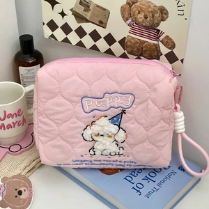 Detail of pink quilted cosmetic bag featuring puppy embroidery and heart patterns