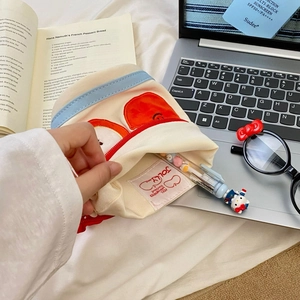 Canvas pencil case with apple embroidery and blue trim, placed on a laptop keyboard