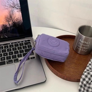 Détail d'une pochette en toile violette avec fermeture éclair et dragonne sur un bureau