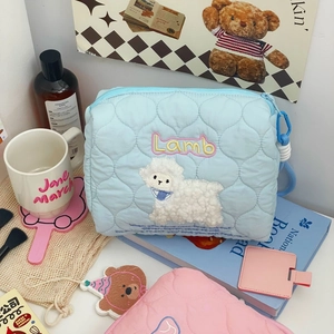 Close-up of light blue quilted makeup bag featuring a cute lamb embroidery pattern