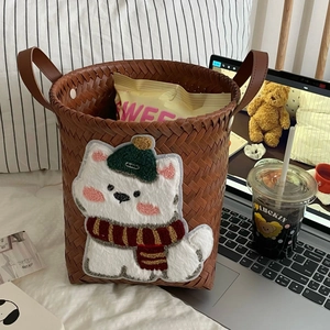Detail of dark brown woven storage basket with white 3D plush cat embroidery and handles