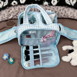 Detailed view of the large blue gingham makeup bag open with multiple storage compartments