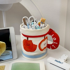 Detail of cup-shaped canvas pencil case with JOLLY embroidery and apple applique