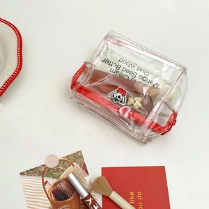 Flat lay of a transparent PVC makeup bag with red trim and cute cartoon koala accessories