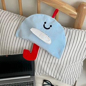 Détail du sac à mouchoirs en peluche bleue en forme de parapluie sur un lit en bois