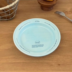 Vue détaillée d'une assiette en céramique bleu clair avec motifs de lettres sur bois