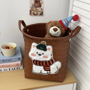 Detail of woven laundry basket featuring dog embroidery and faux leather handles